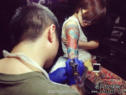 给一坚强的美女在做花臂纹身图案作品现场